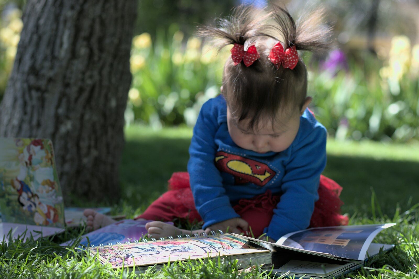 Photo by KV MG a little girl sitting in the grass reading a book